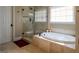 A well lit bathroom with an oval soaking tub and an elegant tile shower with glass door enclosure at 8035 Magnolia Way, Roswell, GA 30075
