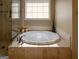 This bathroom has a beautiful oval soaking tub and a glass shower, with a window offering plenty of natural light at 8035 Magnolia Way, Roswell, GA 30075
