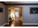Hallway featuring hardwood floors, soft lighting, and a view into an open space enhancing depth at 8035 Magnolia Way, Roswell, GA 30075