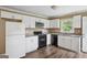 Well-lit kitchen features white cabinets, a black oven and granite countertops at 1854 Shadydale Se Ave, Atlanta, GA 30315