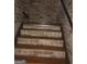 Basement staircase featuring wooden treads, textured brick walls, and a wooden handrail at 1744 Campbell Rd, Covington, GA 30014