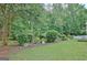 Well-manicured backyard featuring green lawn, lush landscaping, and mature trees for privacy at 323 Newfield Way, Peachtree City, GA 30269