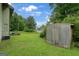 Backyard featuring a wooden shed, lush green grass, some lawn equipment, and surrounding trees at 3570 Keels Ln, Atlanta, GA 30349