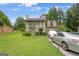 View of the two-story home with lush lawn and trees in background, two parked cars, and a glimpse of the roof at 3570 Keels Ln, Atlanta, GA 30349