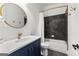 Elegant bathroom features a navy vanity with gold hardware, a round mirror, and tiled shower/tub combo at 1102 Maybeck Way, Peachtree City, GA 30269