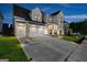Night shot of a stunning two-story home with a two-car garage and a beautifully lit driveway at 1102 Maybeck Way, Peachtree City, GA 30269