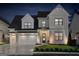 Stunning two-story home with white siding, black accents, and an inviting front porch, beautifully illuminated at night at 1102 Maybeck Way, Peachtree City, GA 30269