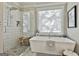 Elegant bathroom featuring a soaking tub, a glass-enclosed shower, and a large window at 395 W Mcintosh Rd, Brooks, GA 30205
