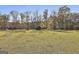 Wide shot of a spacious backyard with a wooden playground nestled among mature trees at 395 W Mcintosh Rd, Brooks, GA 30205