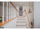 Carpeted staircase with wooden railings and elegant chandelier, enhancing the home's architectural charm at 7392 N Mitchell Ct, Villa Rica, GA 30180