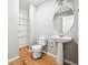 Half bathroom featuring a pedestal sink, round mirror, and wood-look flooring at 1875 Cutleaf Creek Rd, Grayson, GA 30017