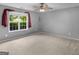 Cozy carpeted bedroom with a ceiling fan and a bright window overlooking a green yard at 230 Cobblestone Ln, Mcdonough, GA 30252