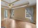 Bright main bedroom with a tray ceiling, ceiling fan, two windows, and wood-look floors at 230 Cobblestone Ln, Mcdonough, GA 30252
