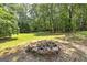 Stone fire pit surrounded by mature trees in a spacious backyard at 100 Riveredge Dr, Mcdonough, GA 30252