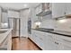 Modern kitchen featuring stainless steel appliances, white cabinetry, granite countertops, and hardwood floors at 411 Southbridge Pass, Peachtree City, GA 30269