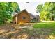 Exterior view of brick home featuring a deck, lush greenery, and mature trees at 195 Youngs Cir, Fayetteville, GA 30215