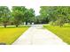 Concrete driveway leads to a home surrounded by lush green trees and well-maintained lawn at 1183 Iron Gate Blvd, Jonesboro, GA 30238