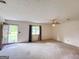 Bright living room with neutral carpet, a ceiling fan, and large windows for natural light at 1183 Iron Gate Blvd, Jonesboro, GA 30238