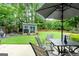 Landscaped backyard with a patio set under an umbrella and a shed at 407 Calgary Dr, Peachtree City, GA 30269