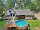 Backyard with a large wooden deck, above ground pool, lounge chairs, and well manicured lawn at 130 Emerald Dr, Mcdonough, GA 30253