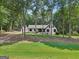 Charming house with white exterior, black shutters, and a green front yard with mature trees at 130 Emerald Dr, Mcdonough, GA 30253