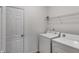 This bright laundry room features a washer, dryer, wire rack, and a door at 305 Overland Trl, Temple, GA 30179