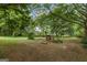 Spacious backyard with mature trees, a small animal enclosure, and a partially bare ground at 98 Maddox Dr, Mcdonough, GA 30252
