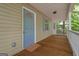 Close up shot of home entrance and covered front porch with wooden floor and blue door at 438 Punkintown Rd, Villa Rica, GA 30180