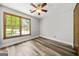 Bedroom with wood-look flooring, ceiling fan, and a large window filling the space with light at 409 Deergrass Trl, Peachtree City, GA 30269
