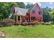 Exterior view of a red home with a deck, grill, and lush backyard featuring mature trees and landscaping at 3498 Overland Trl, Ellenwood, GA 30294