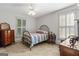 Cozy bedroom with a metal frame bed, shuttered windows, and vintage dresser at 3498 Overland Trl, Ellenwood, GA 30294