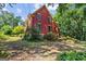 Charming two-story home with red siding, green shutters, and stone foundation nestled in a lush landscape at 3498 Overland Trl, Ellenwood, GA 30294