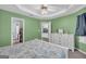 A cozy bedroom with green walls, white trim, and a tray ceiling with ceiling fan provides a comfortable retreat at 136 Glynn Addy Dr, Stockbridge, GA 30281