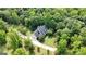 Aerial view showcases a home nestled among trees with a winding driveway and well-manicured lawn at 1561 Aiken Chafin Ln, Mcdonough, GA 30252
