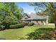 View of the backyard with well-maintained lawn, mature trees, and brick home in the background at 1561 Aiken Chafin Ln, Mcdonough, GA 30252