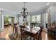 Elegant dining room with a decorative chandelier, wood table, and scenic backyard views at 1561 Aiken Chafin Ln, Mcdonough, GA 30252