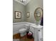 Elegant powder room with pedestal sink, decorative mirror and artwork at 1561 Aiken Chafin Ln, Mcdonough, GA 30252