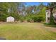 Beautiful backyard with green grass, mature trees, and storage building at 85 Bloomfield Way, Sharpsburg, GA 30277