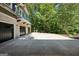 Spacious three-car garage with black doors, driveway, a balcony, and surrounded by trees at 508 Hastings Dr, Peachtree City, GA 30269