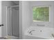 Bright bathroom with a glass shower, large soaking tub, and a window with natural light at 506 Brewer Dr, Locust Grove, GA 30248