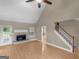 Bright living room featuring a fireplace, a ceiling fan, and a staircase at 506 Brewer Dr, Locust Grove, GA 30248