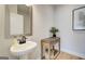 Cozy powder room with pedestal sink, decorative mirror, and wooden side table, offering a charming space at 43 Avian Way # 3B, Auburn, GA 30011
