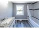 Bathroom featuring a shower/tub combination, large window, and gray cabinets with granite countertop at 1919 101 S Hwy, Temple, GA 30179