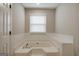Large soaking tub beneath window with tiled walls and a built-in seat at 870 Rutherford Dr, Dacula, GA 30019