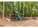 Wooded playground area featuring a swing set, slide, and climbing wall with a seating bench at 870 Rutherford Dr, Dacula, GA 30019