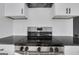 Close-up of a stainless steel stove, white subway tile backsplash, and white cabinets with black hardware at 1226 Byewood Sw Ln, Atlanta, GA 30310