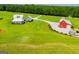 Aerial view of a modern farmhouse with a red barn and sprawling green land at 385 Liberty Church Rd, Carrollton, GA 30116