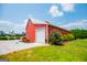 Side view of the red barn with a white garage door and small trees in the front with gravel driveway at 385 Liberty Church Rd, Carrollton, GA 30116