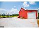 View of red barn with a white garage door and a nice home is shown in the background with a gravel driveway at 385 Liberty Church Rd, Carrollton, GA 30116