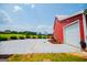 View of barn with a white garage door and gravel driveway with a nice, blue home in the background at 385 Liberty Church Rd, Carrollton, GA 30116